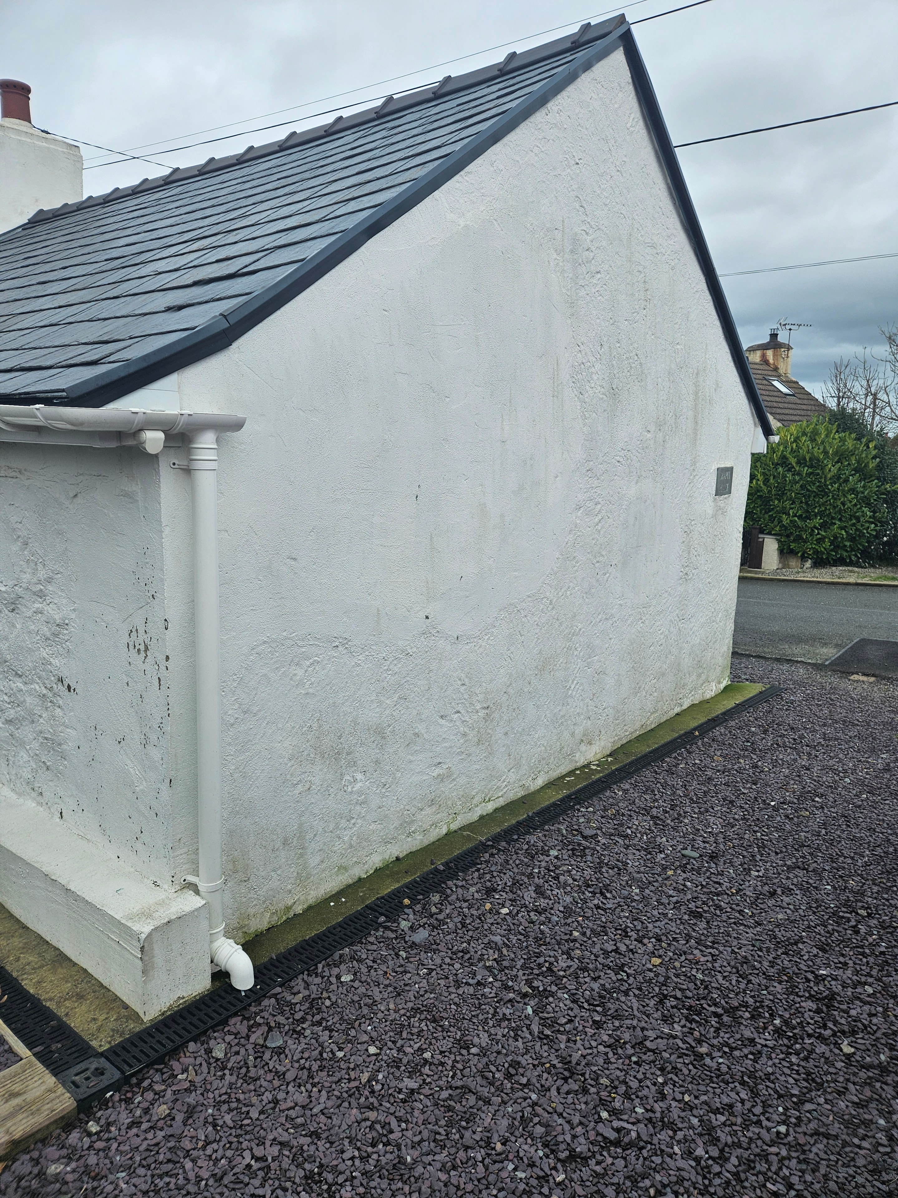 Cottage exterior with weathered and flaking paint before preparation in Hermon, Anglesey