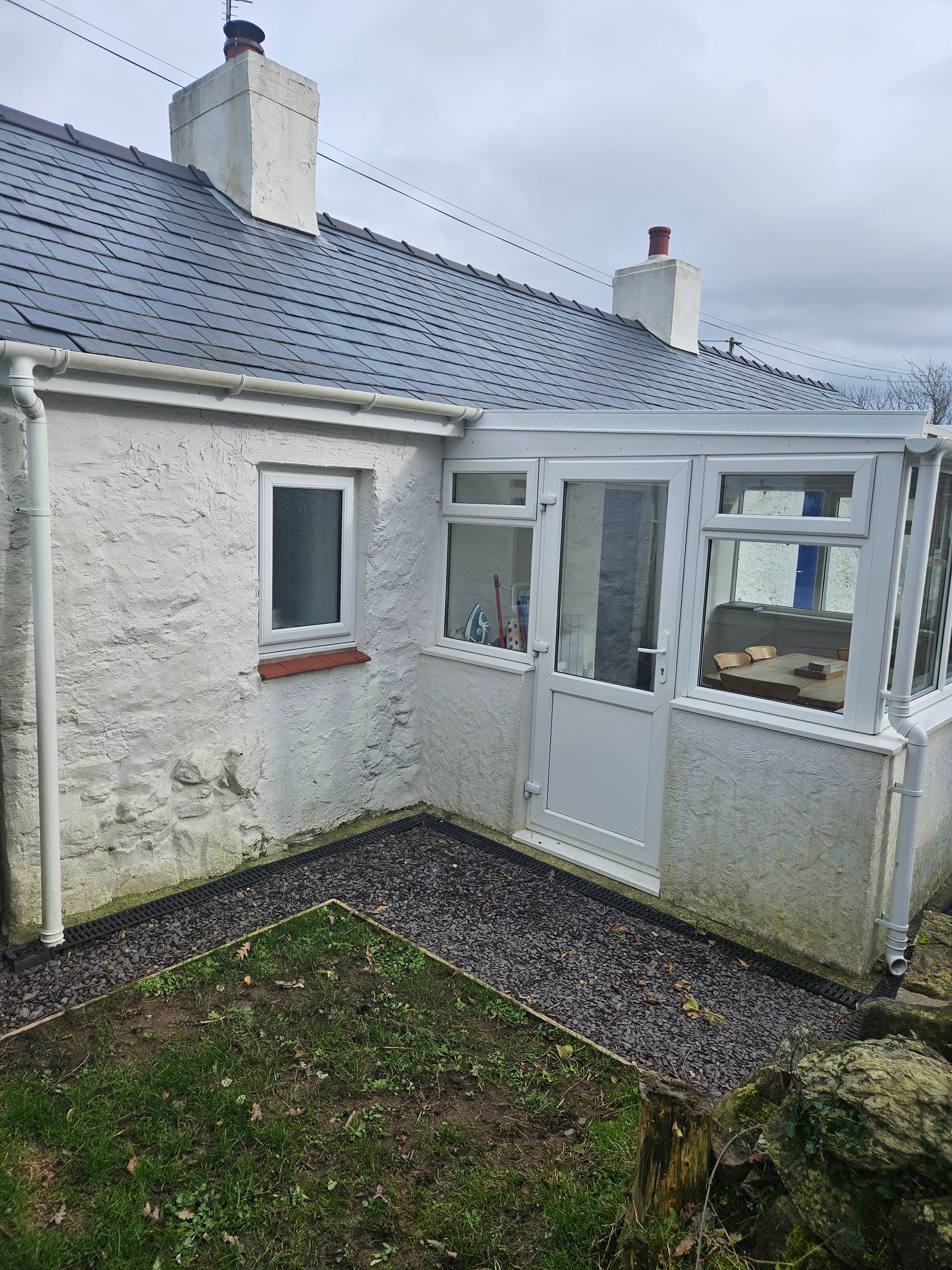 Cottage exterior with weathered and flaking paint before preparation in Hermon, Anglesey — second view